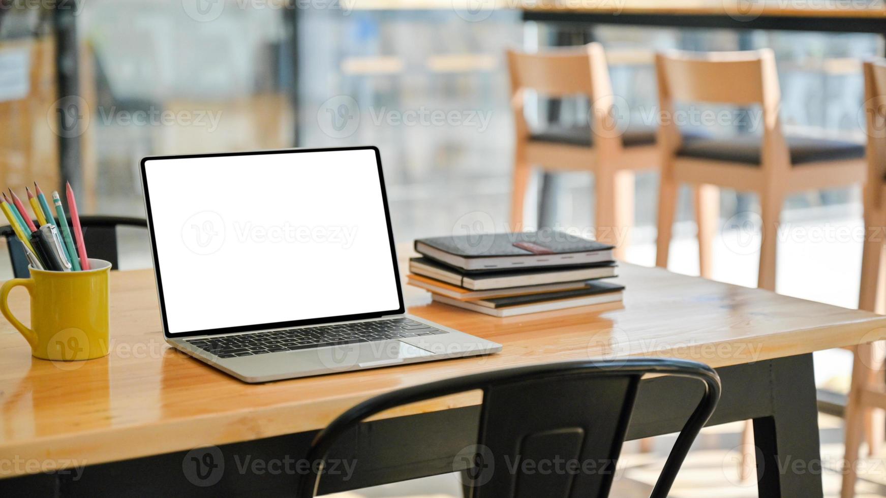 abgeschnittene Aufnahme von Laptop mit Notebooks und Schreibwaren auf einem Holzschreibtisch in einem modernen Büro. foto