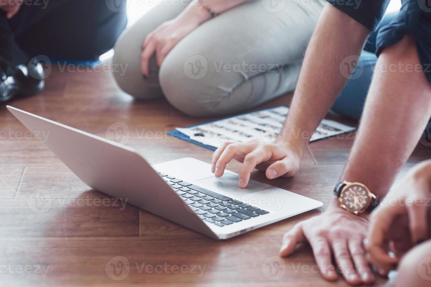 Nahaufnahme. Gruppe junger Geschäftsleute arbeitet mit Laptop zusammen. Freiberufler sitzen auf dem Boden. Zusammenarbeit Unternehmenserfolg. Teamwork-Konzept foto