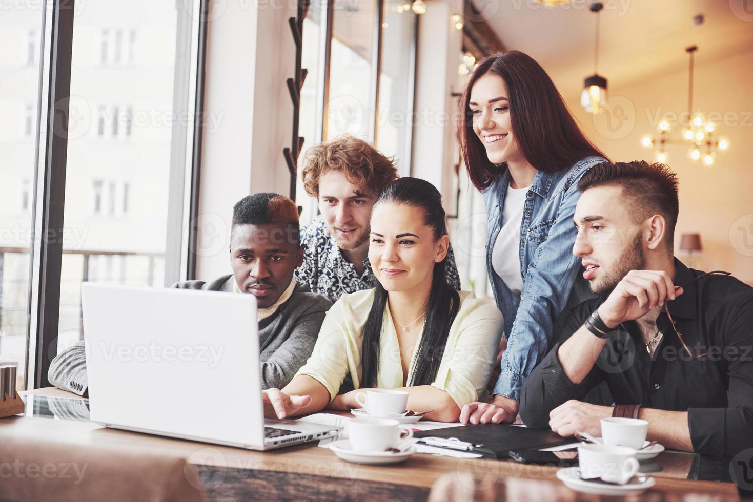 Multiethnische Geschäftsleute, Unternehmer, Unternehmen, Kleinunternehmenskonzept, Frau, die Kollegen etwas auf dem Laptop zeigt, während sie sich um einen Konferenztisch versammeln? foto