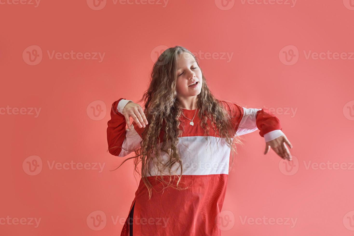 junge schöne süße Mädchen tanzen auf rotem Hintergrund, moderne schlanke Hip-Hop-Stil Teenager-Mädchen springen foto