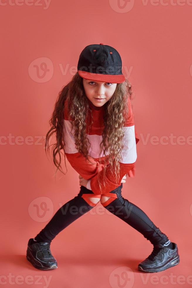 junge städtische Frau tanzt auf rotem Hintergrund, moderne schlanke Hip-Hop-Stil-Teenager-Mädchen foto