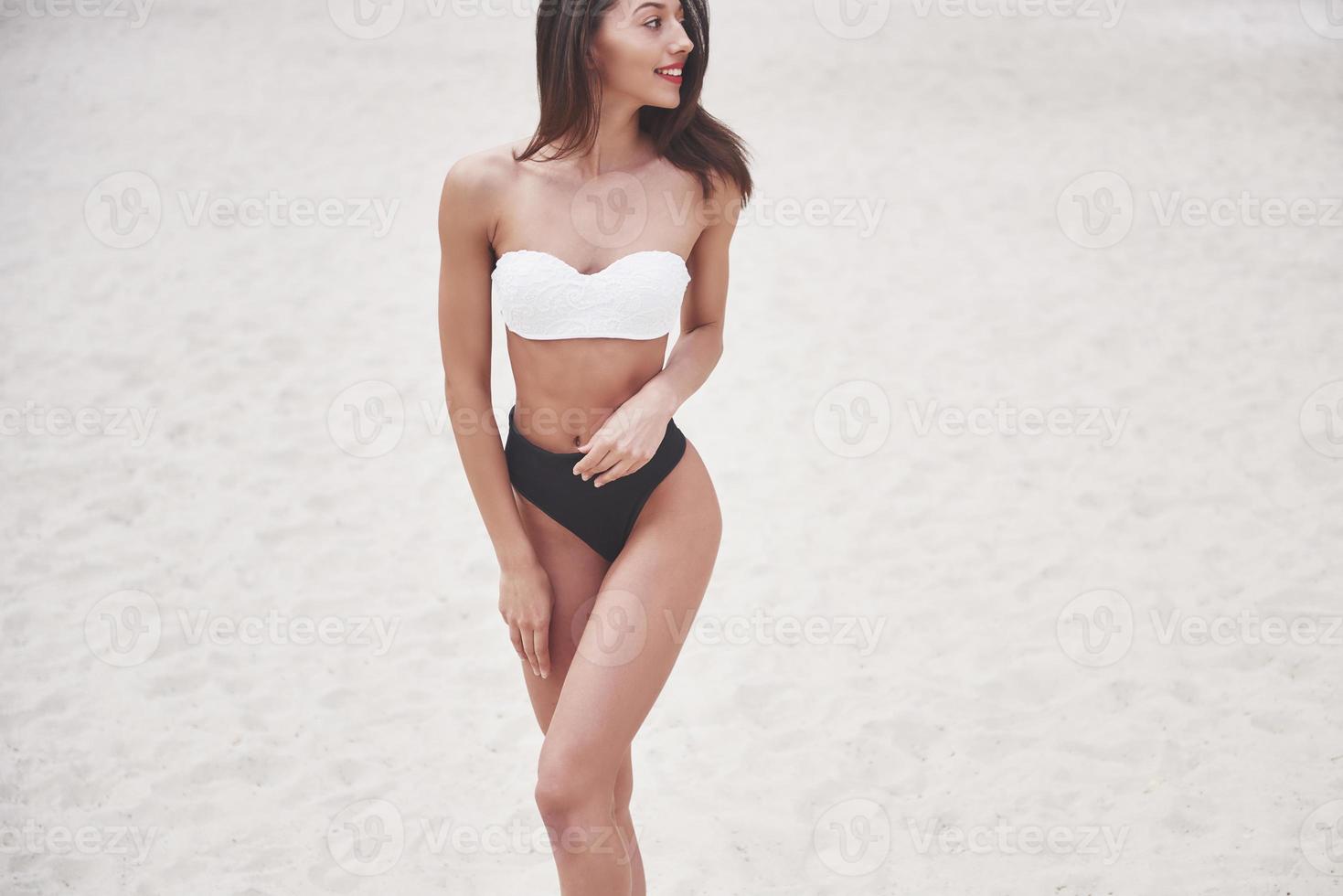 Schönes schlankes Luxusmädchen im Bikini am Sandstrand auf einer tropischen Insel. sexy gebräunter Körper und perfekte Figur foto