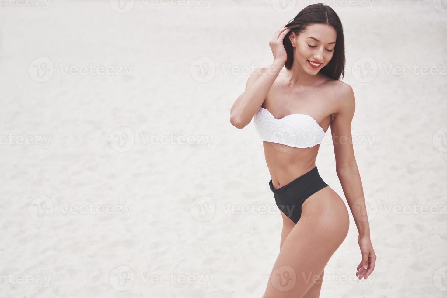 Schönes schlankes Luxusmädchen im Bikini am Sandstrand auf einer tropischen Insel. sexy gebräunter Körper und perfekte Figur foto