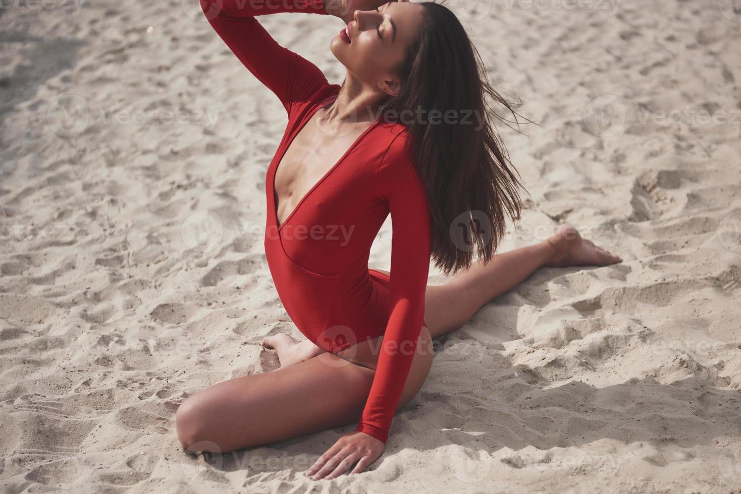 schöne junge gebräunte Frau im roten Bikini posiert am Strand. sexy Modelportrait mit perfektem Körper. Sommerurlaub Konzept foto