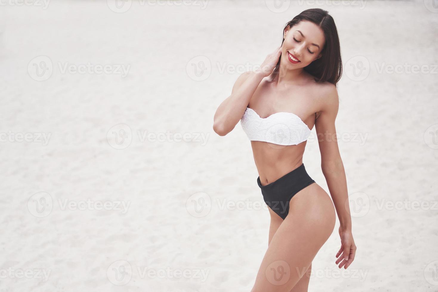 Schönes schlankes Luxusmädchen im Bikini am Sandstrand auf einer tropischen Insel. sexy gebräunter Körper und perfekte Figur foto