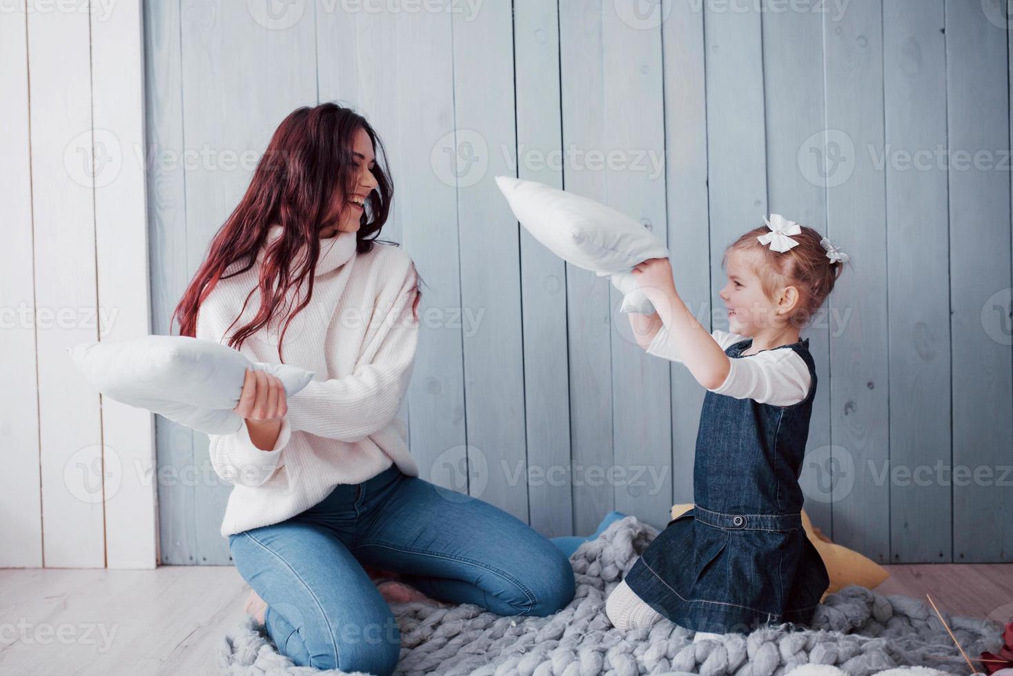 glückliche familie die mutter und ihr kind kämpfen gegen kissen. fröhliche familienspiele foto