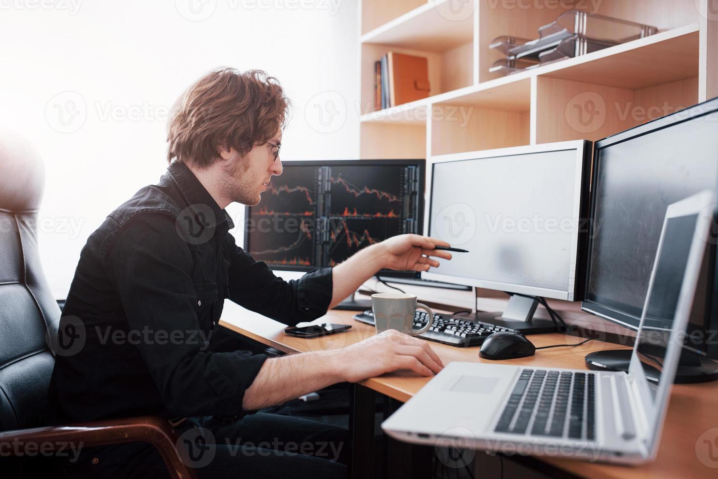 stressiger Tag im Büro. junger Geschäftsmann, der die Hände auf seinem Gesicht hält, während er am Schreibtisch im Kreativbüro sitzt. Börsenhandel Forex Finance Grafikkonzept foto