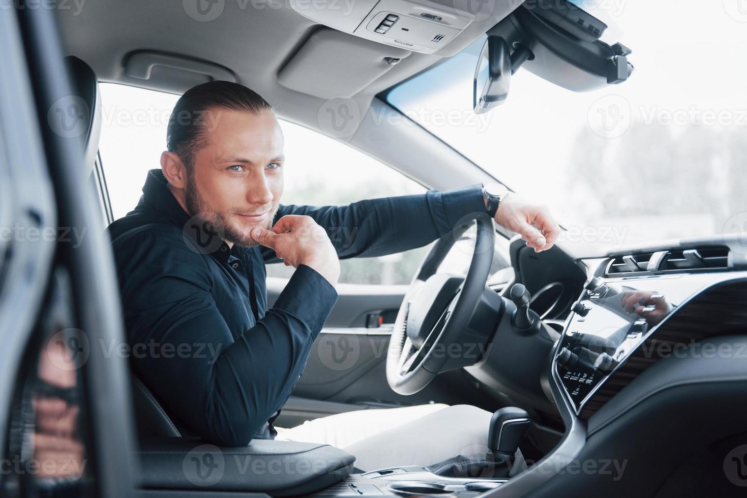 selbstbewusster junger Geschäftsmann, der am Steuer seines neuen Autos sitzt foto