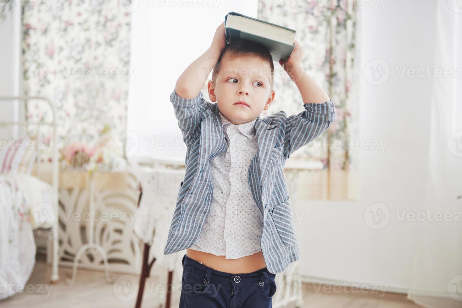 Foto eines fleißigen Schülers mit Buch auf dem Kopf will nicht studieren und zur Schule gehen. der schüler hat es satt, hausaufgaben zu machen