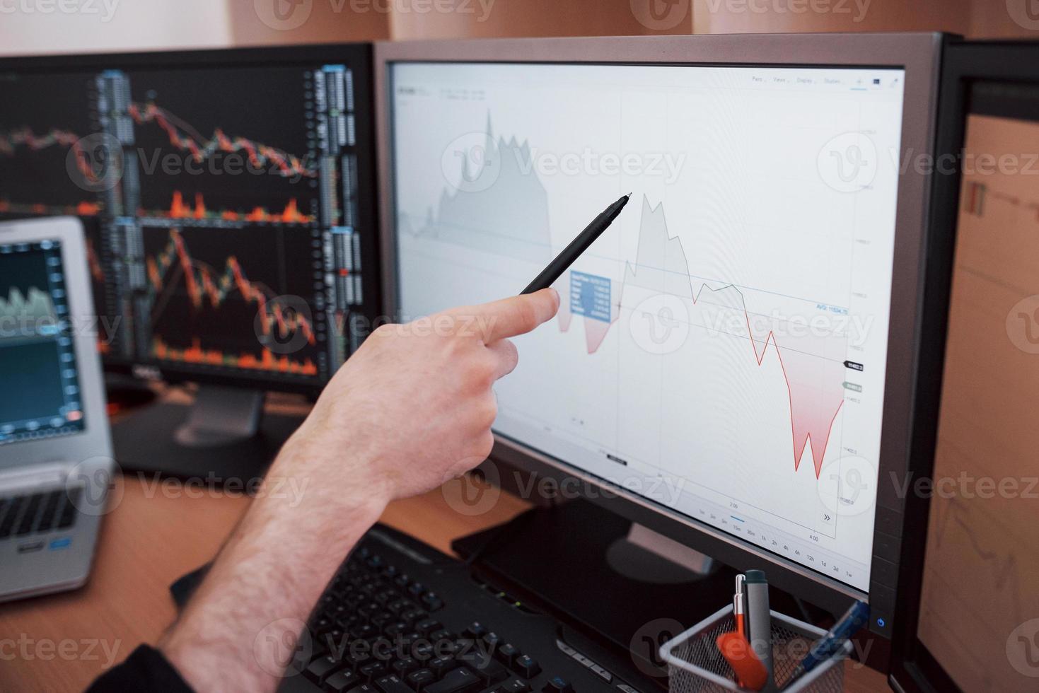 Daten analysieren. Nahaufnahme eines jungen Geschäftsmannes, der mit Stift auf die im Diagramm dargestellten Daten zeigt, während er im Kreativbüro arbeitet foto