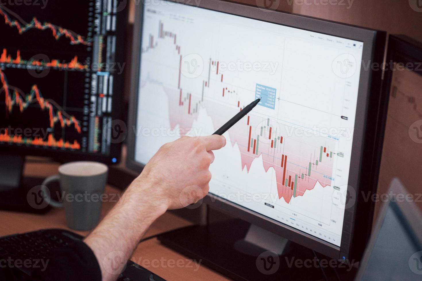 Daten analysieren. Nahaufnahme eines jungen Geschäftsmannes, der mit Stift auf die im Diagramm dargestellten Daten zeigt, während er im Kreativbüro arbeitet foto