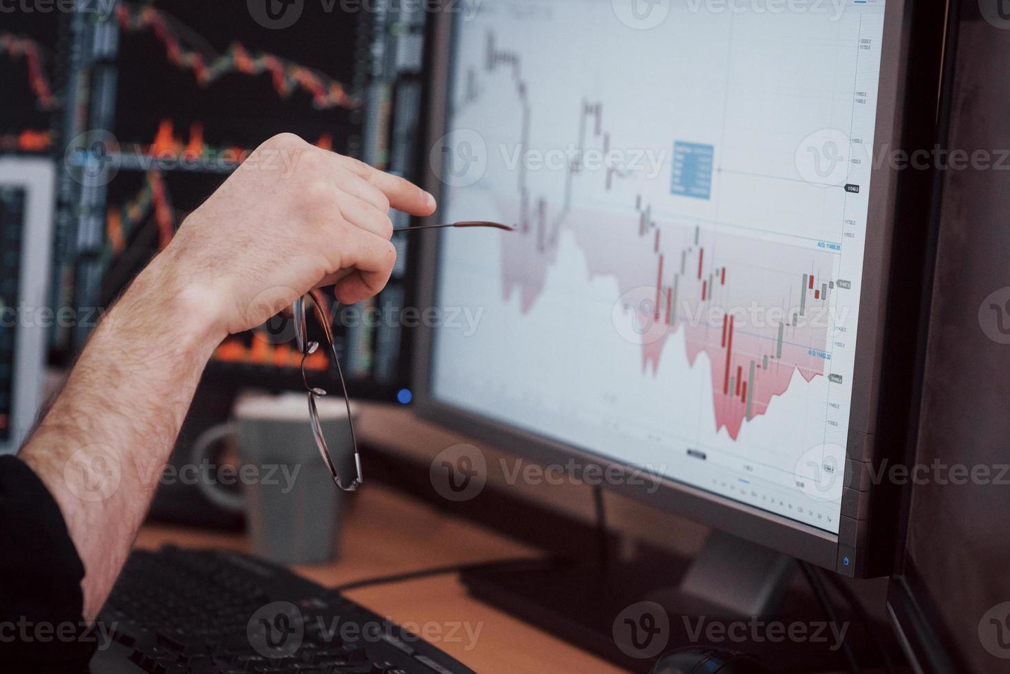 Daten analysieren. Nahaufnahme eines jungen Geschäftsmannes, der mit Stift auf die im Diagramm dargestellten Daten zeigt, während er im Kreativbüro arbeitet foto