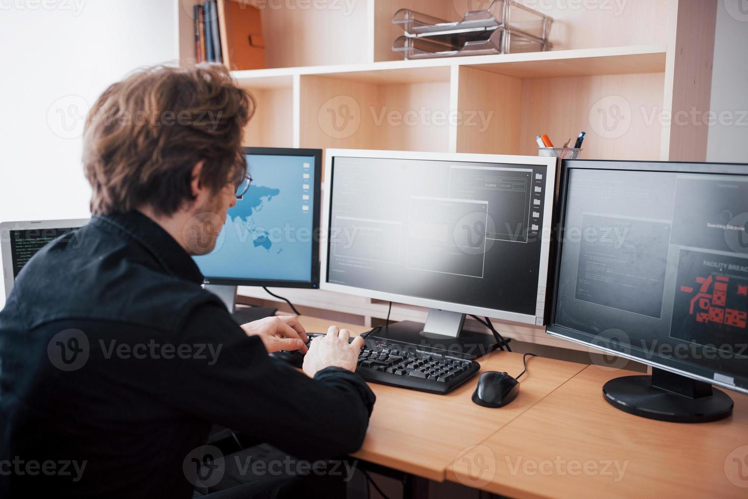 Männlicher Programmierer, der an einem Desktop-Computer mit vielen Monitoren im Büro in einer Softwareentwicklungsfirma arbeitet. Website-Design-Programmierung und Codierungstechnologien foto