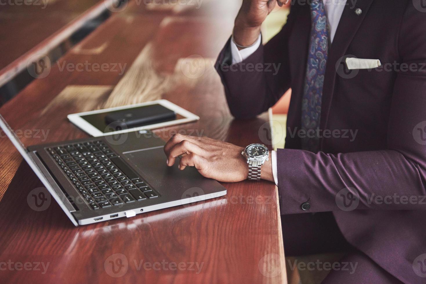 Eine schöne, stilvolle afroamerikanische Geschäftsfrau, die einen Anzug trägt, benutzt ihren Laptop während der Arbeit foto