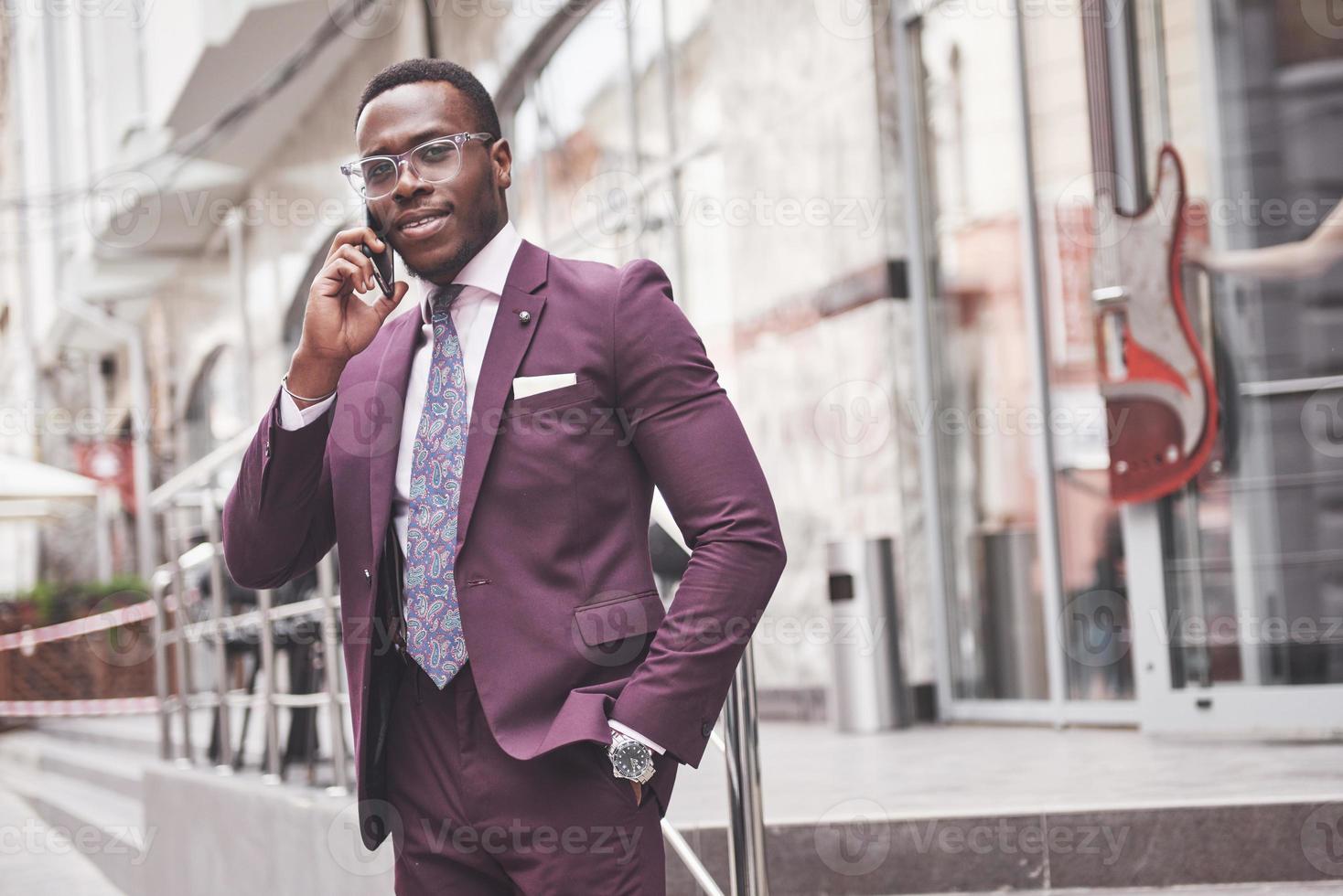 Porträt eines jungen und gutaussehenden afroamerikanischen Geschäftsmannes, der in einem Anzug am Telefon spricht foto