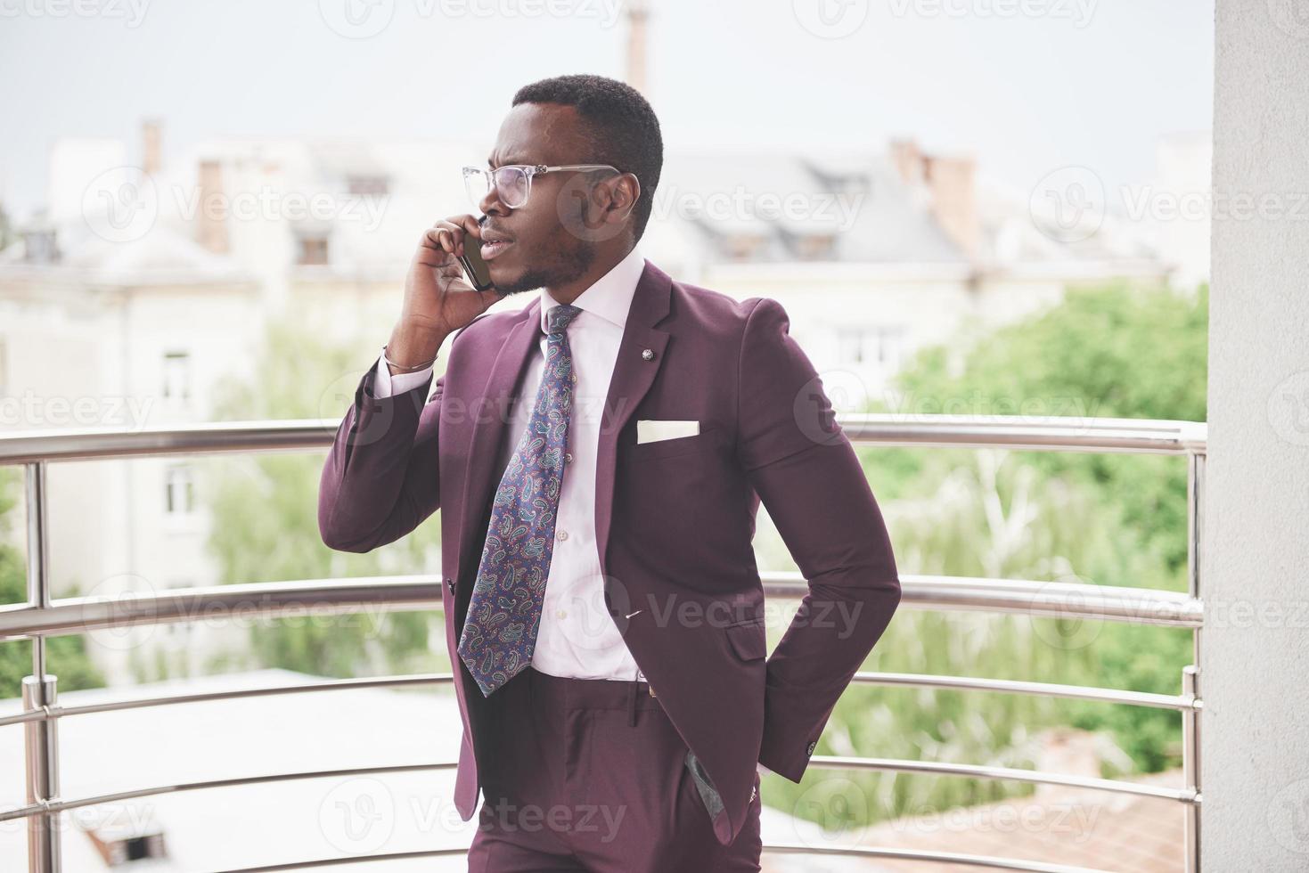 Porträt eines jungen und gutaussehenden afroamerikanischen Geschäftsmannes, der in einem Anzug am Telefon spricht foto
