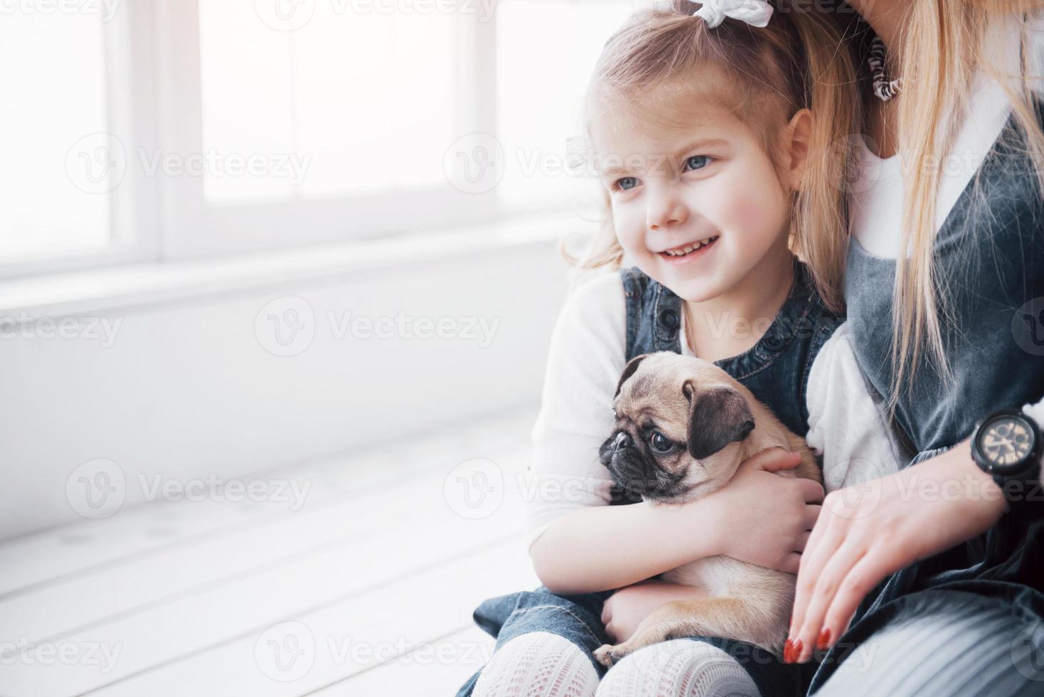 glückliche liebevolle Familie. Mutter und ihre Tochter Kind Mädchen spielen und umarmen entzückenden Mops foto