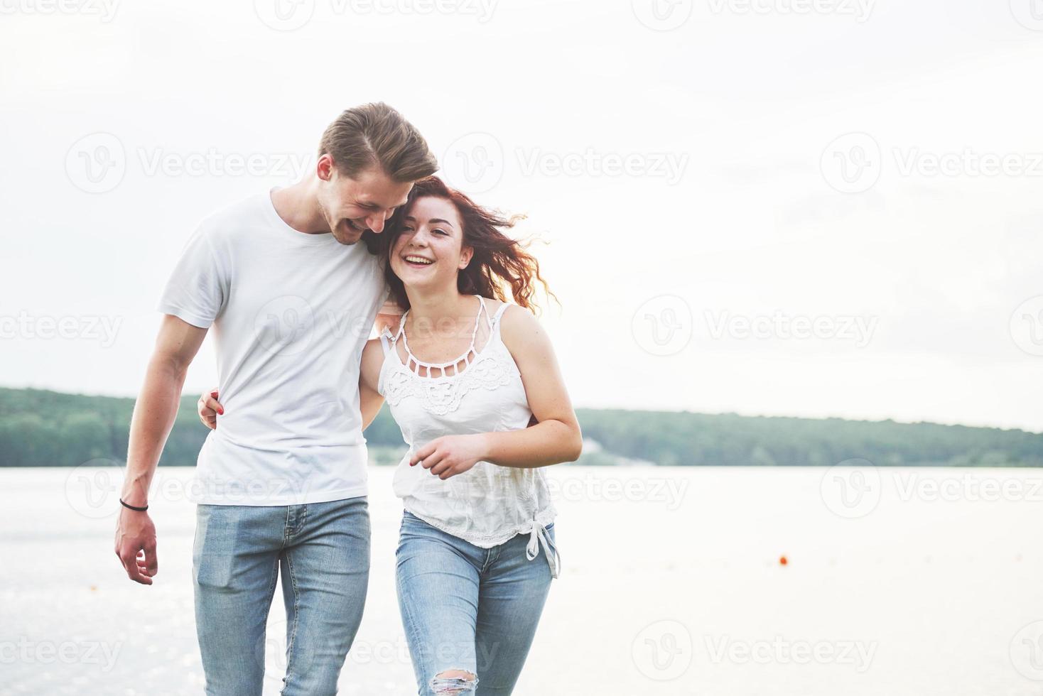 glückliches junges Paar, das einen einsamen Strand backriding genießt foto
