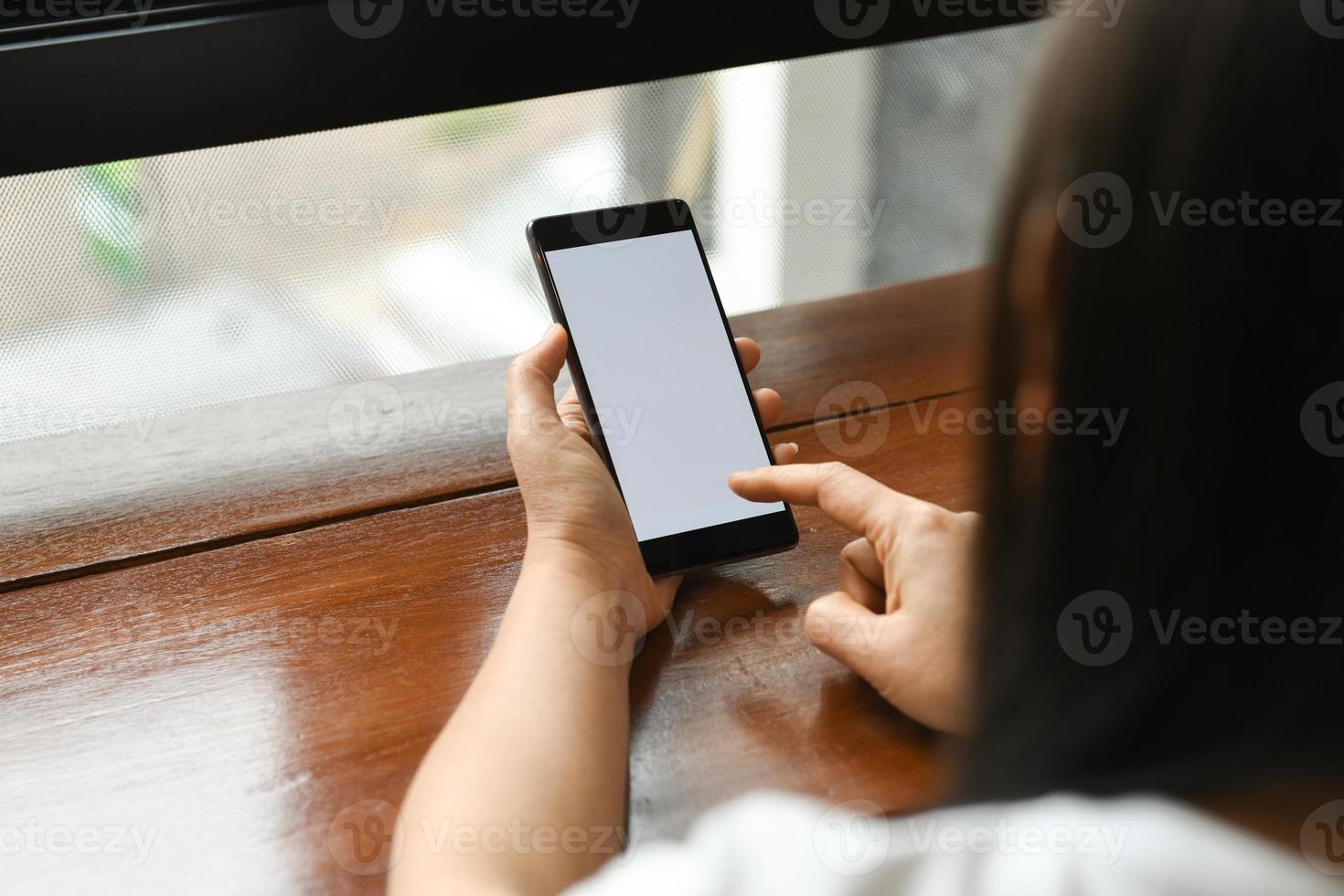 Frau, die weißes Bildschirmmodell-Smartphone hält und berührt. foto