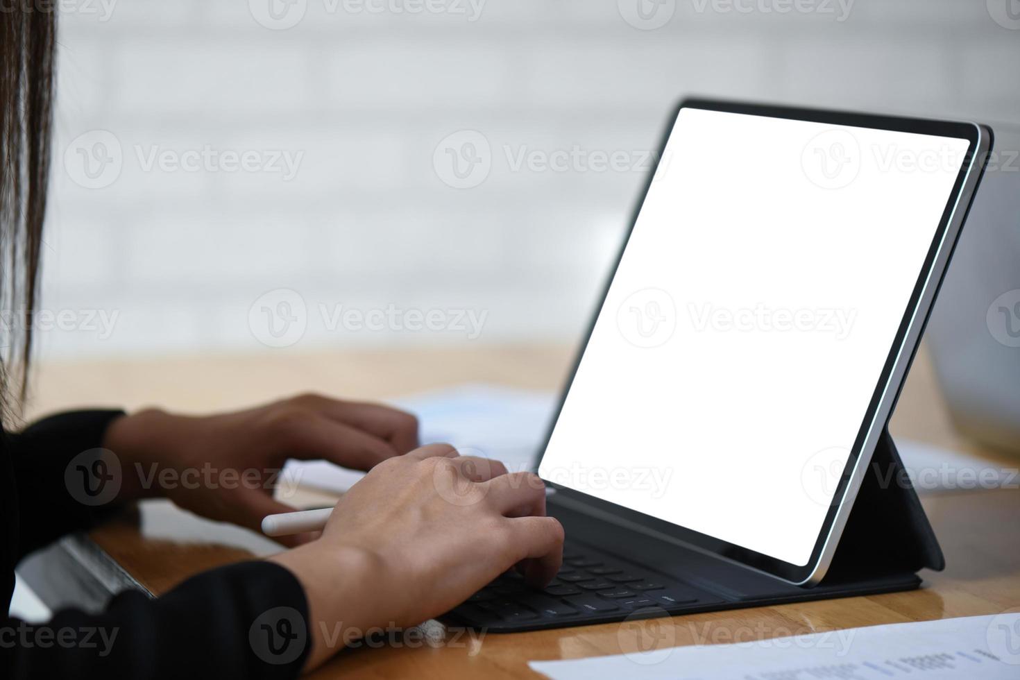 Geschäftsfrau, die an einem weißen Bildschirm-Tablet-Computer mit Grafiken auf Holztisch arbeitet. foto