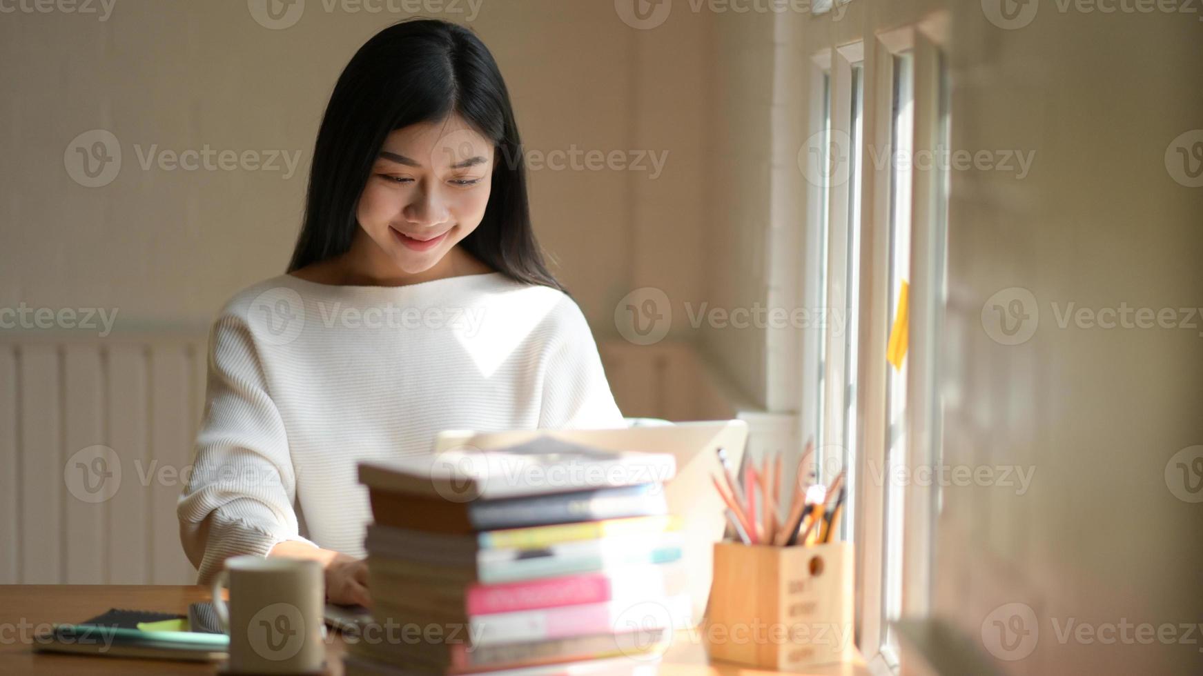 7/8-Aufnahme eines asiatischen Teenager-Studentenmädchens, das ein Projekt für die Abschlussarbeit mit Entschlossenheit vorbereitet. foto