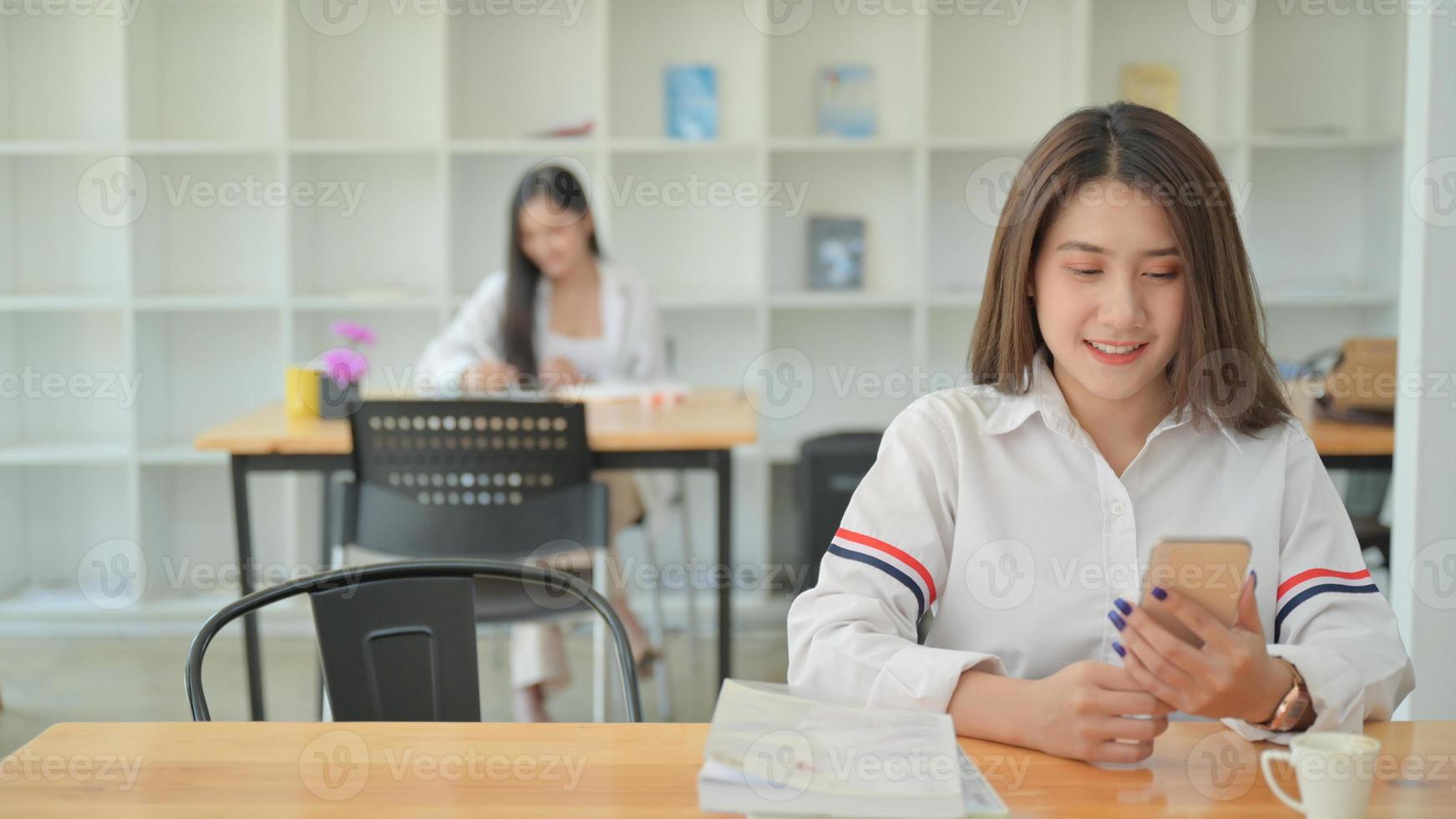 Eine junge Frau mit weißem Hemd benutzt ein Smartphone in einem modernen Büro. foto