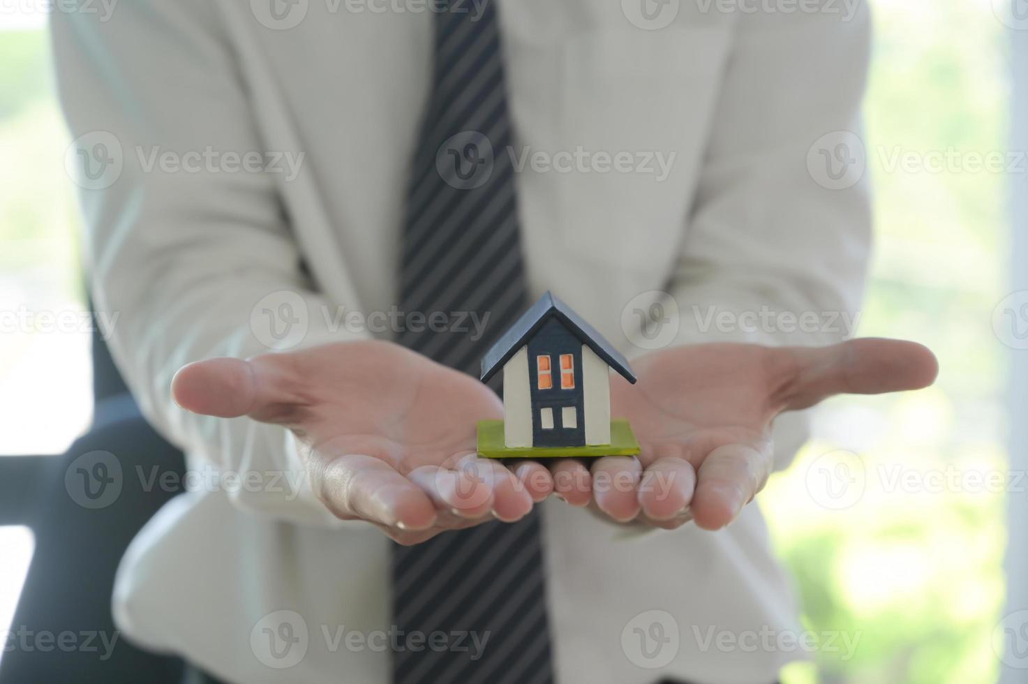 Hauskaufkonzept, Hausmakler, der ein Musterhaus in der Hand hält, um es den Kunden zu präsentieren. foto