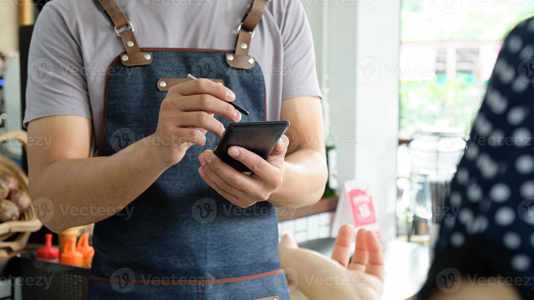 Mitarbeiter hält ein Smartphone, um das Menü der Kundenbestellung zu speichern. foto