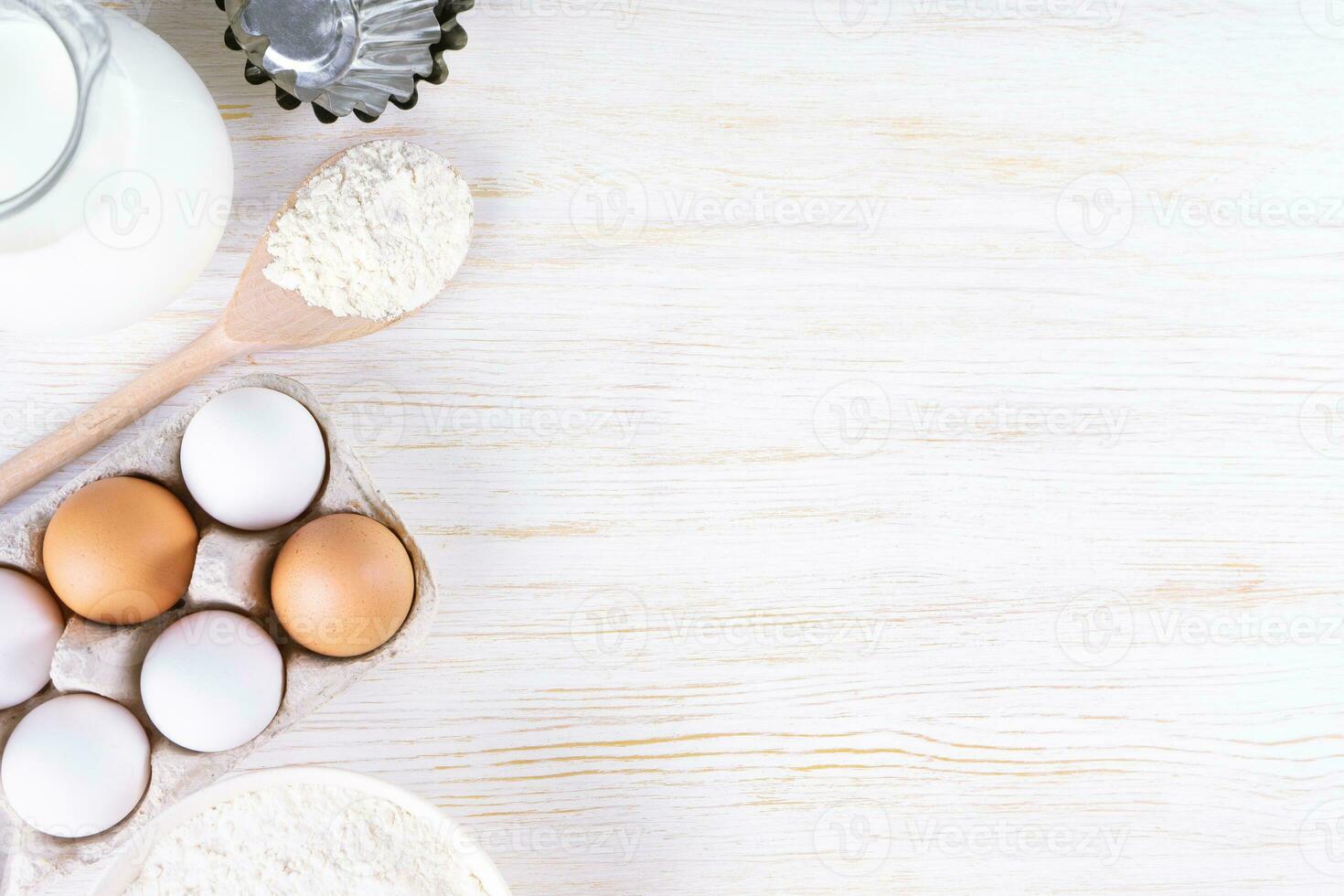 backzutaten mehl, eier, milch, backformen auf weißem holzhintergrund mit kopienraum foto