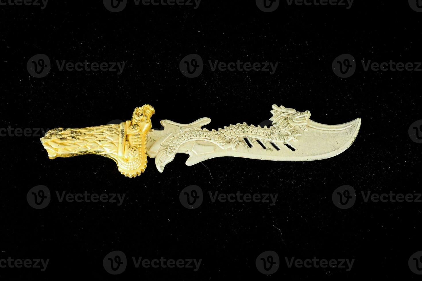 ein geschnitzt Gold und Weiß Messer mit ein Drachen auf es foto