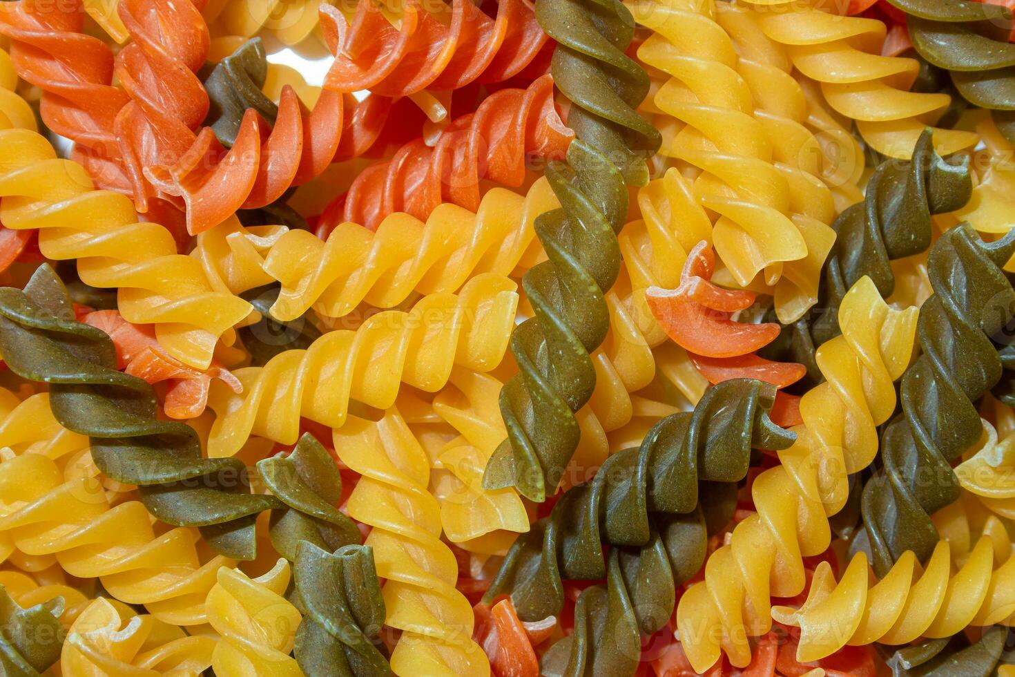 ungekocht beschwingt farbig Fusilli Pasta. ein faszinierend kulinarisch Segeltuch von mehrfarbig Spiralen, Erstellen ein lebhaft und texturiert Hintergrund zum Gourmet Kochen. farbig trocken Pasta. roh Makkaroni foto