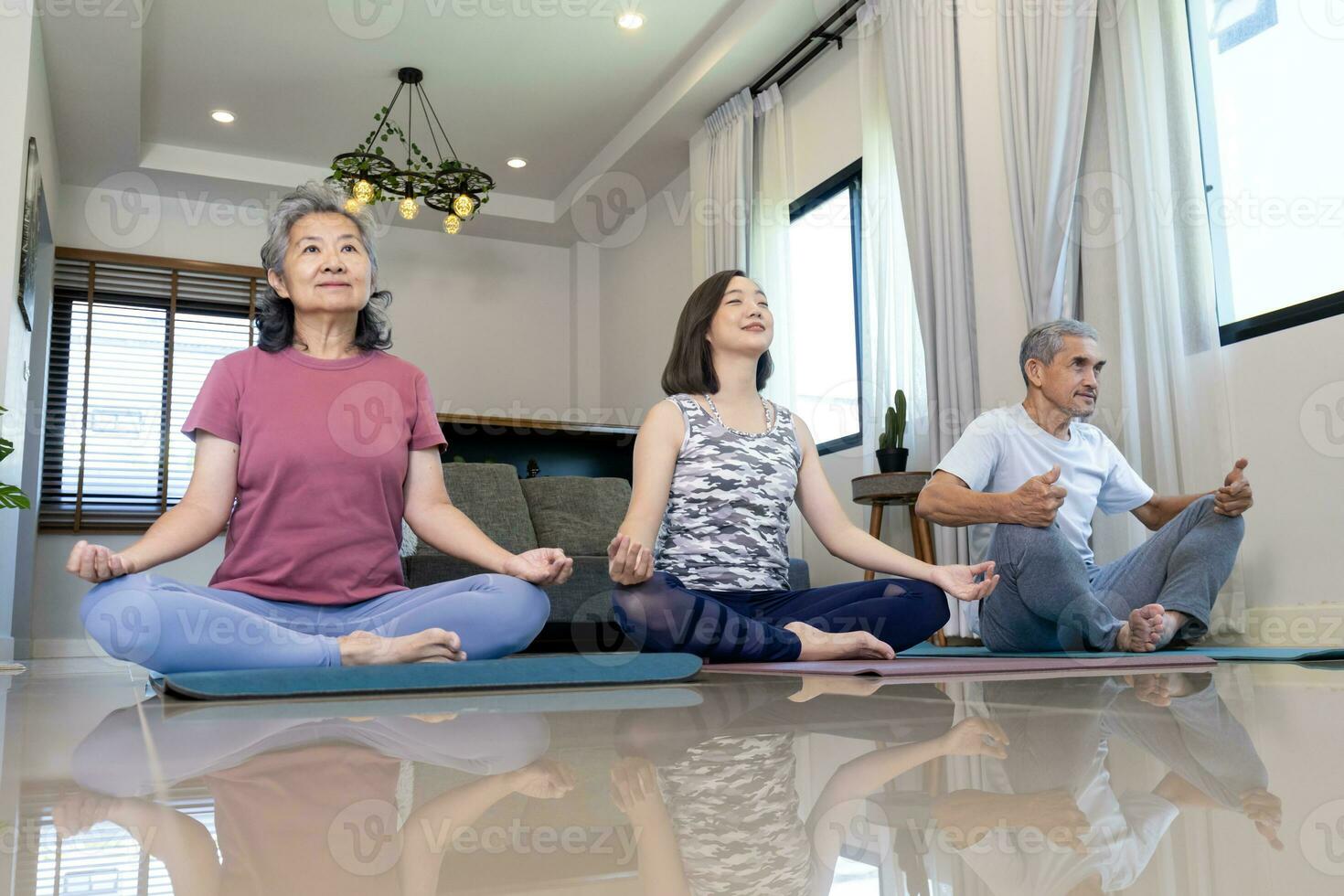 Senior asiatisch Paar und Tochter sind tun trainieren beim Zuhause im Sitzung Meditation Yoga Pose mit entspannend Übung zum ältere gesund Konzept foto