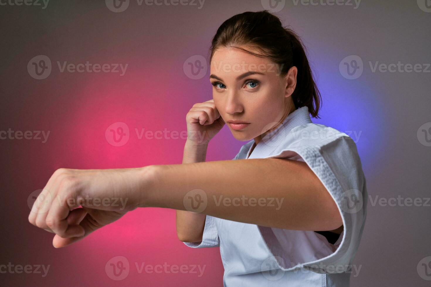 sportlich Frau im traditionell Kimono ist üben Karate im Studio. foto