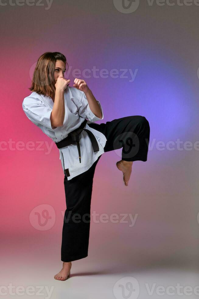 sportlich Frau im traditionell Kimono ist üben Karate im Studio. foto