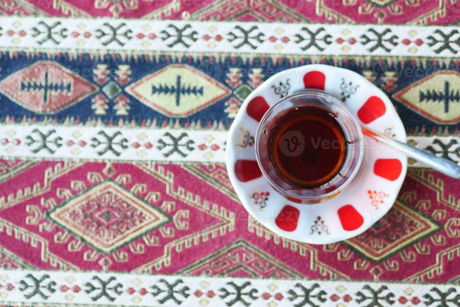rot Türkisch Tee mit traditionell Birne geformt Glas auf gemustert Tischdecke im Cafe foto