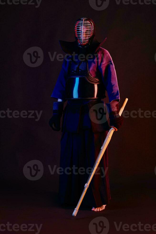 schließen oben Schuss, Kendo Kämpfer tragen im ein Rüstung, traditionell Kimono, Helm üben kriegerisch Kunst mit shinai Bambus Schwert, schwarz Hintergrund. foto