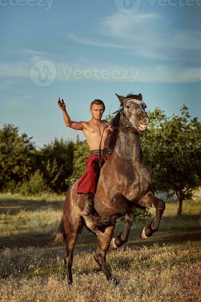 gut aussehend Mann Cowboy Reiten auf ein Pferd - - Hintergrund von Himmel und Bäume foto