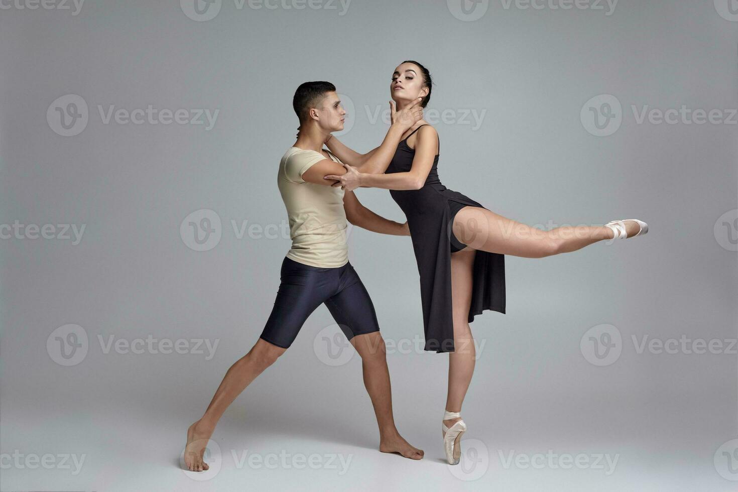 zwei sportlich modern Ballett Tänzer sind posieren gegen ein grau Studio Hintergrund. foto