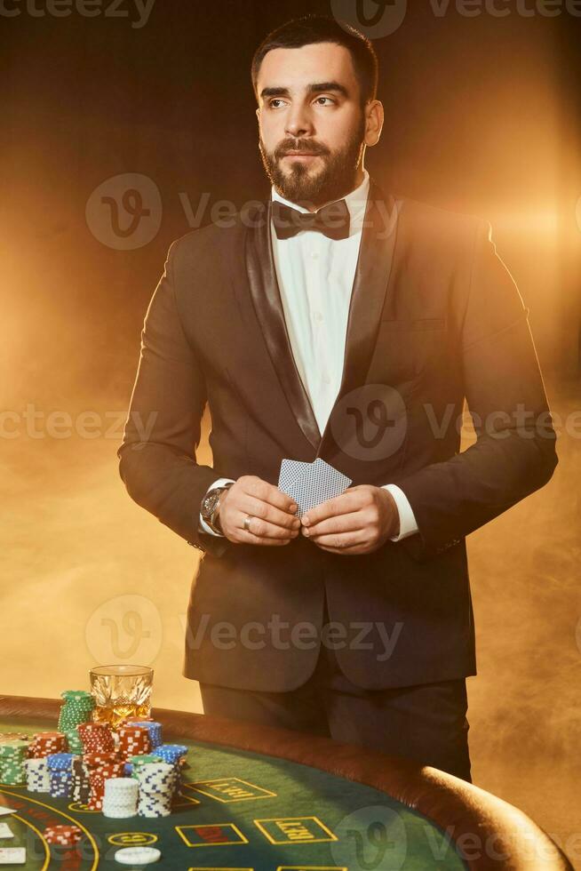 ein jung Mann im ein Geschäft passen Stehen in der Nähe von Poker Tisch. Mann Glücksspiele. foto