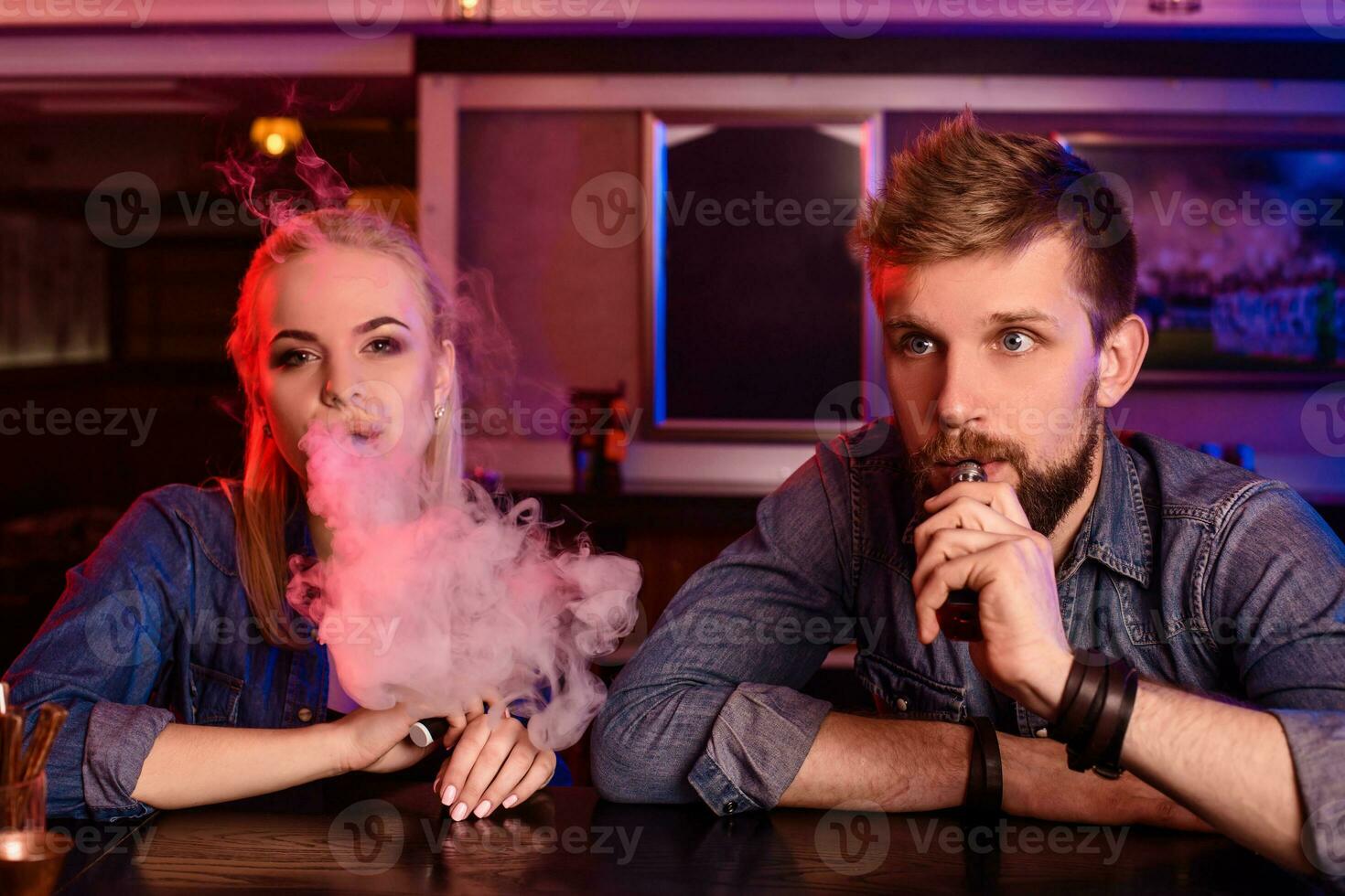 ein Mann und Frau Rauchen elektronisch Zigarette im ein Dampfen Bar. foto