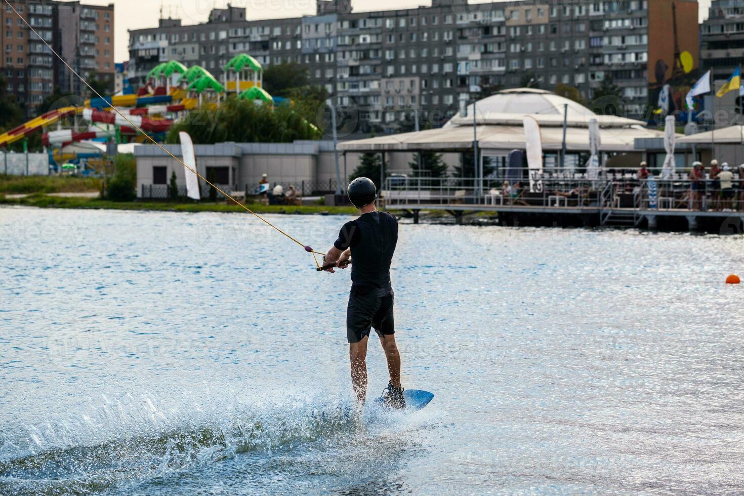 Mann im nass passen und schützend Helm halten Abschleppen Seil und balancieren auf Wakeboard foto