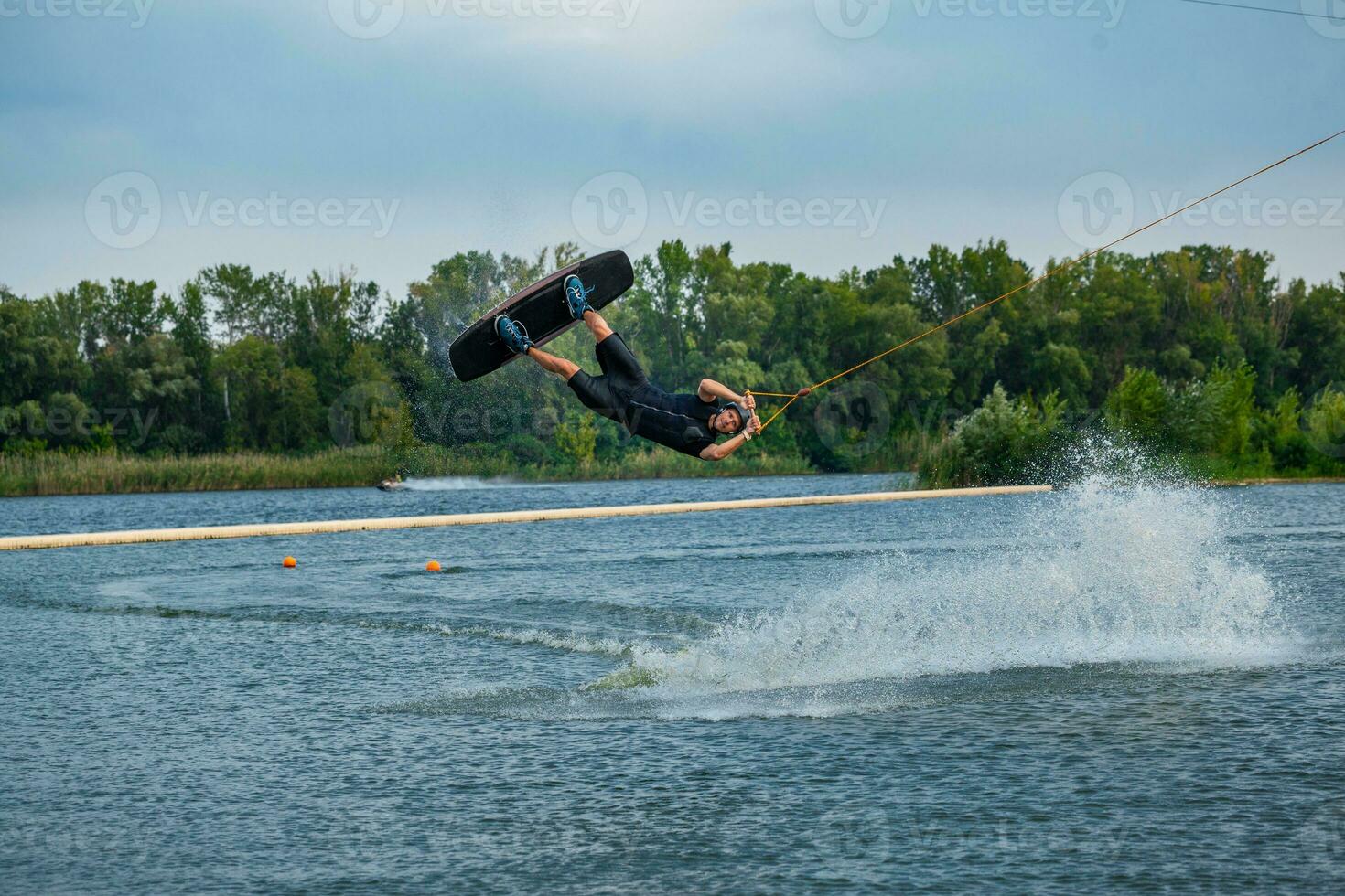 erfahren Wakeboard Fahrer Springen und Spinnen im Luft halten auf zu Abschleppen Kabel foto