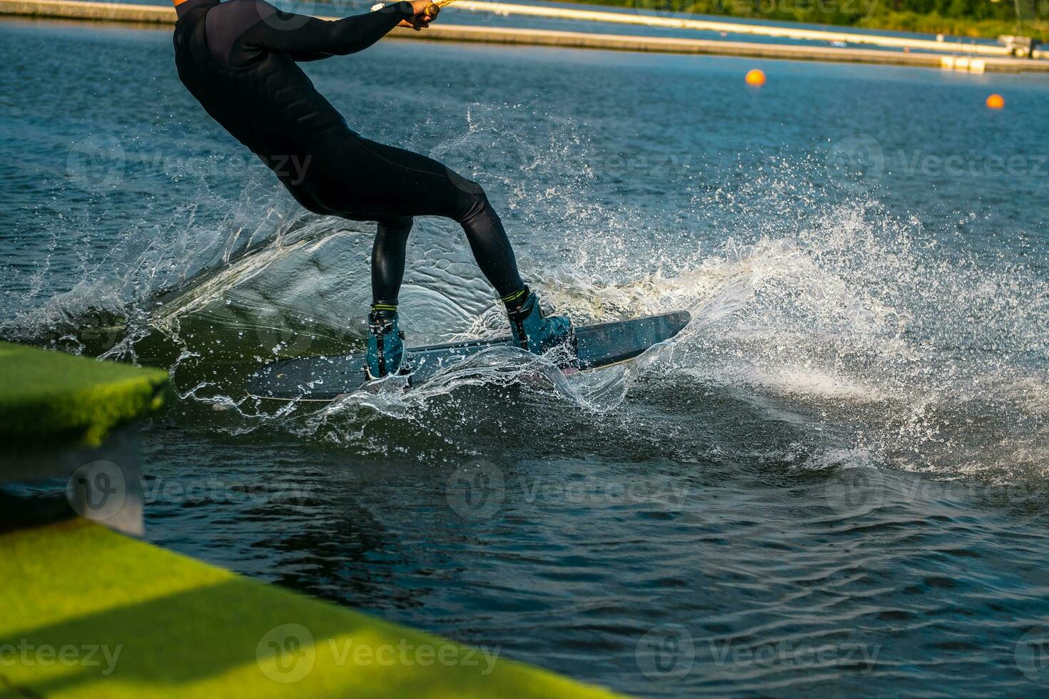 Wakeboarder Schneiden Wasser mit Kante von Tafel Erstellen spritzt während beginnend aus Dock foto