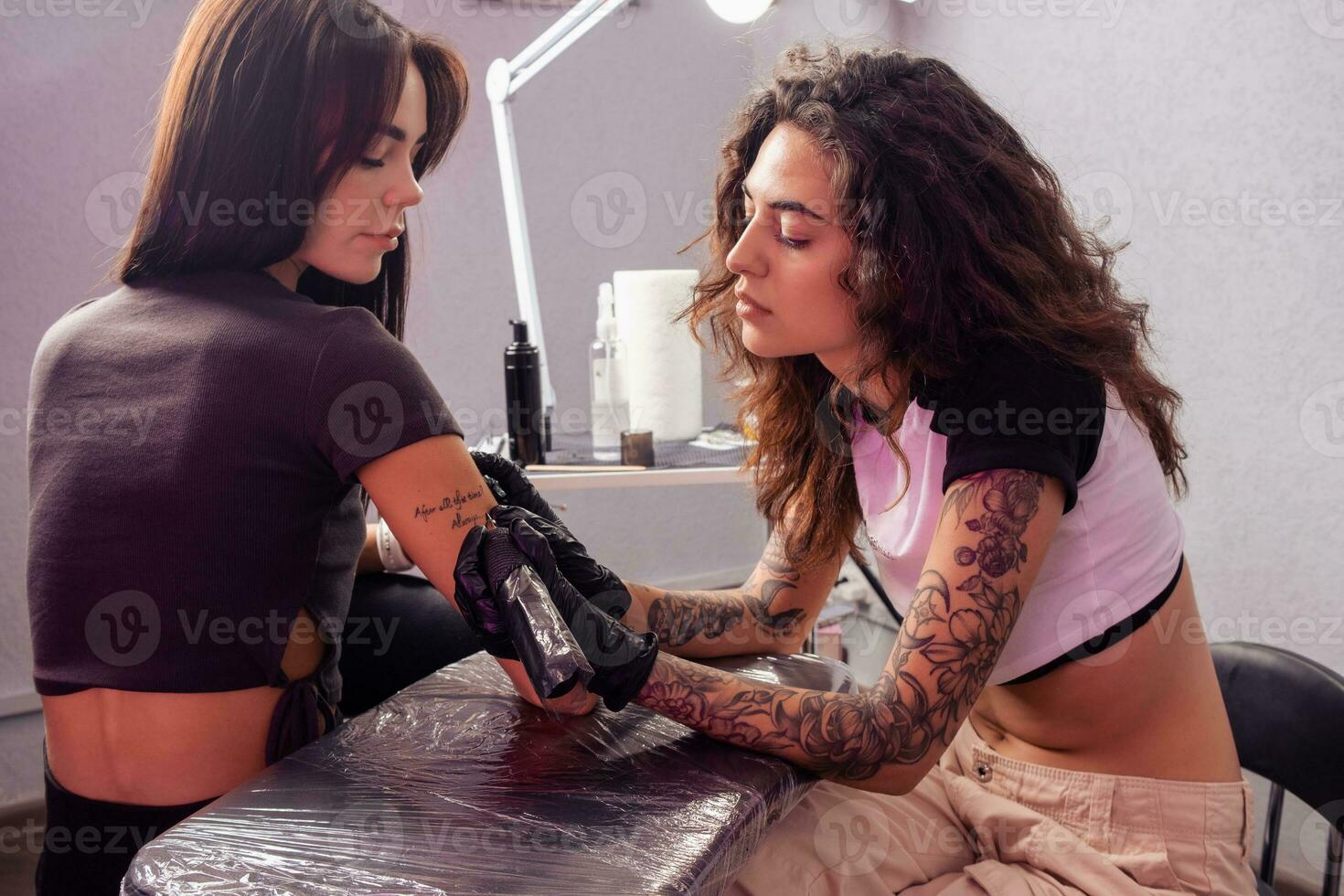 Fachmann weiblich Künstler Erstellen Benutzerdefiniert Beschriftung tätowieren auf Arm von Frau foto