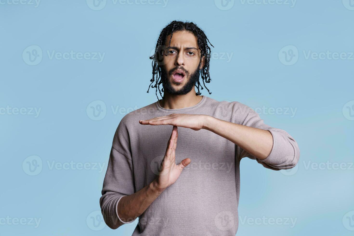 arabisch Mann Herstellung Zeit aus Geste mit Hände und suchen beim Kamera Porträt. gut aussehend jung Person zeigen Unterbrechung Zeichen mit Waffen, nehmen brechen von Kommunikation Konzept foto