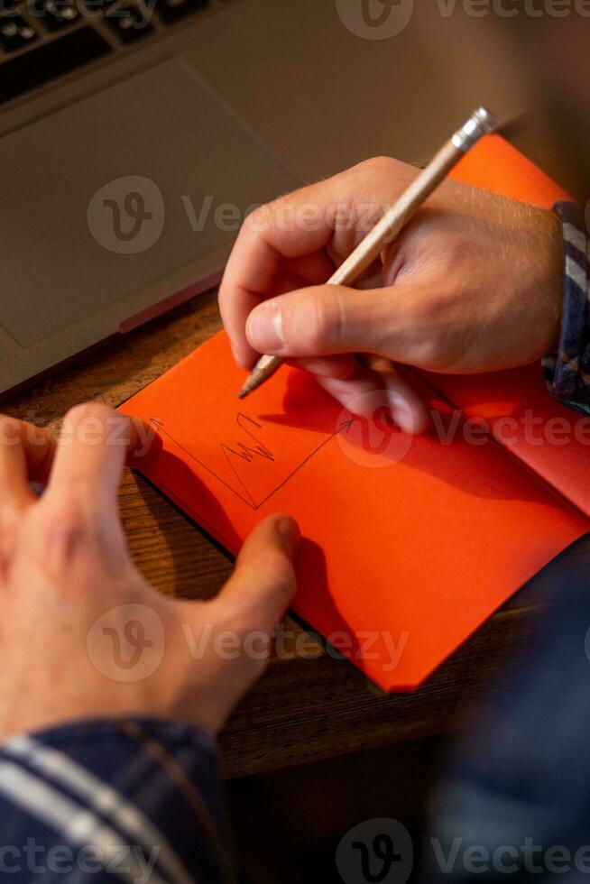 abgeschnitten Bild von beiläufig Geschäft Mann oder Freiberufler Planung seine Arbeit auf Notizbuch, Arbeiten auf Laptop Computer mit Clever Telefon, Tasse von Kaffee auf Tabelle beim Kaffee Geschäft oder Zuhause Büro. foto