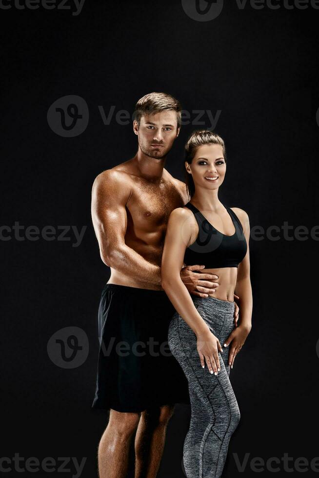 Sport, Fitness, trainieren Konzept. passen Paar, stark muskulös Mann und schlank Frau posieren auf ein schwarz Hintergrund foto