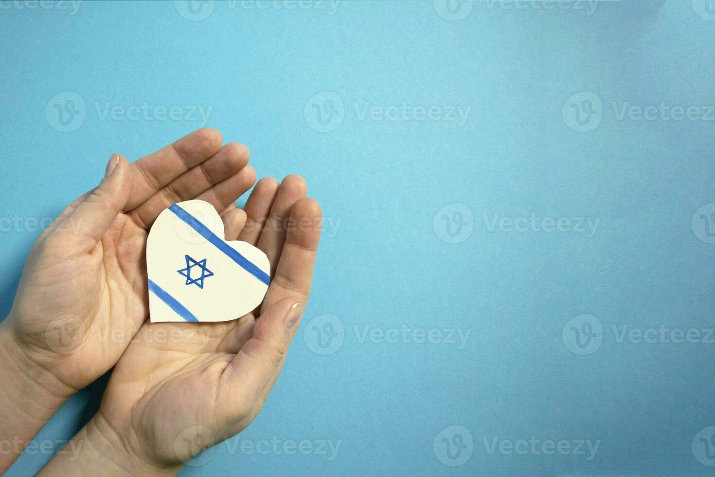 das Konzept von Ende das Krieg im Israel. Herz im das Farben von das Flagge von Israel im weiblich Hände. foto