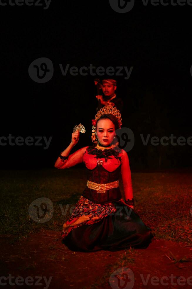 ein weiblich Tänzer im ein rot Kostüm saß im das Stille von das Nacht welche gestärkt das Traurigkeit foto