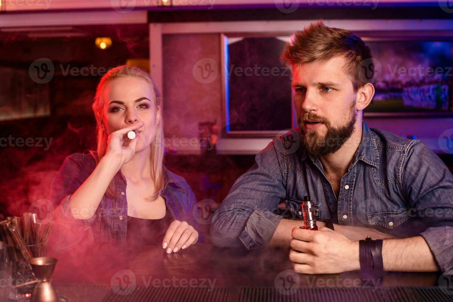 ein Mann und Frau Rauchen elektronisch Zigarette im ein Dampfen Bar. foto